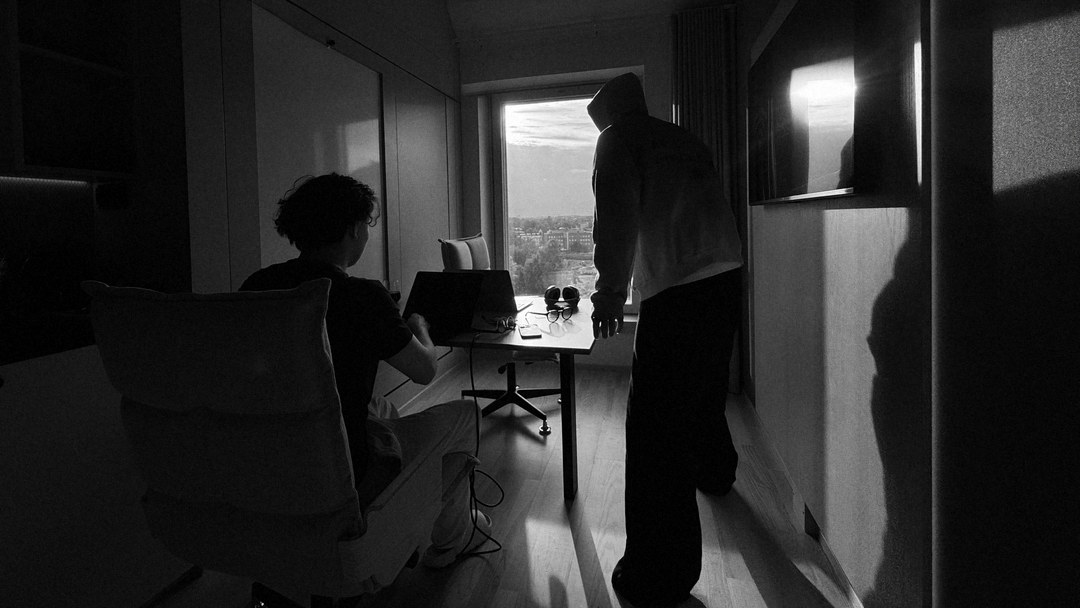 Two people working in a hotel room in Cairo, one at a laptop, one at the window